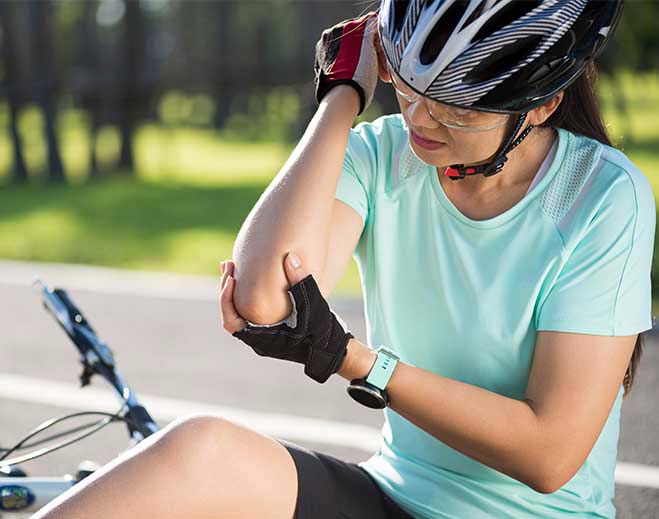 Cyclist holding injured elbow after fall