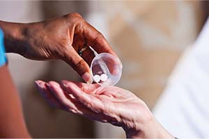 Hand pouring pills into another person's open palm