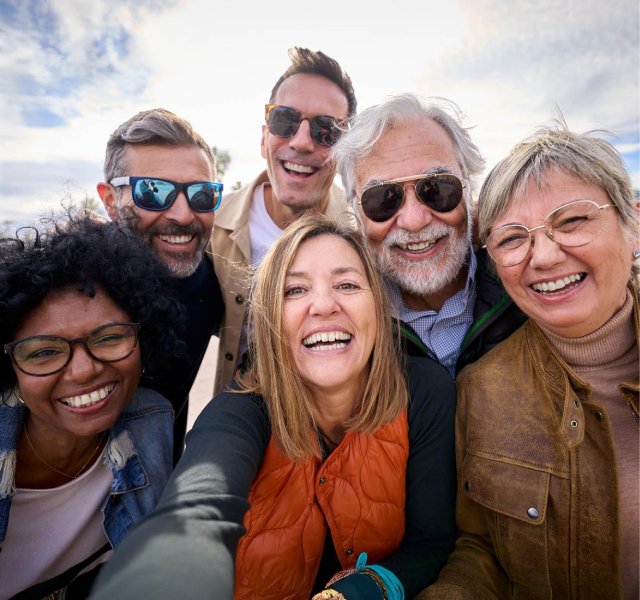 Six people smiling and taking a group selfie together